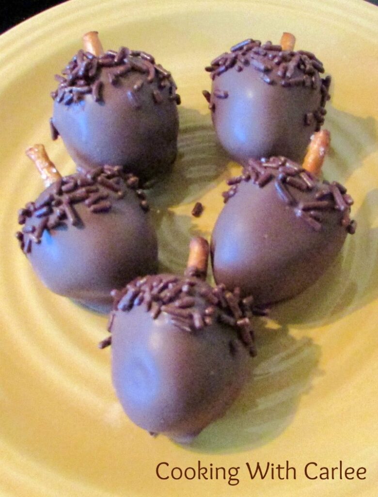 plate of peanut butter Oreo balls shaped like acorns with pretzel stems.