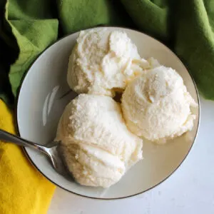 small bowl with 3 scoops of lemon ice cream and a spoon.