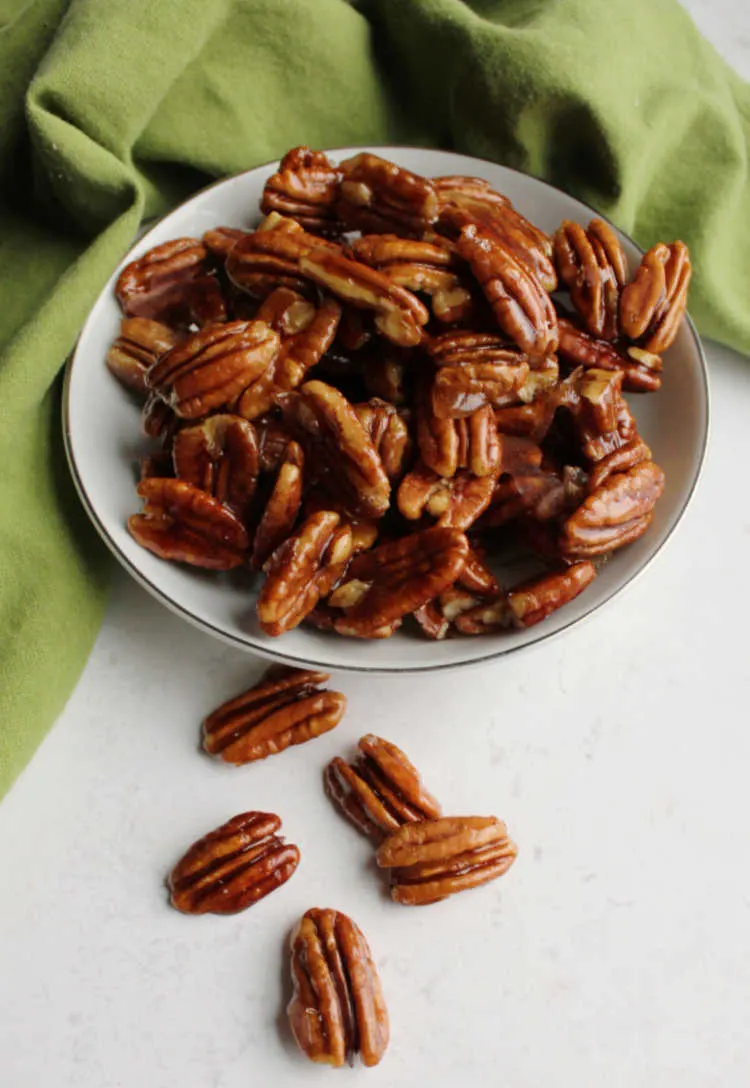honey coated pecans spilling out of bowl.