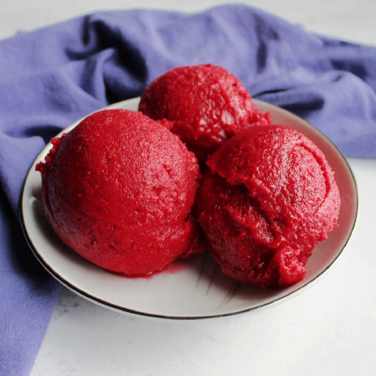3 scoop of deep pink raspberry sorbet in small bowl