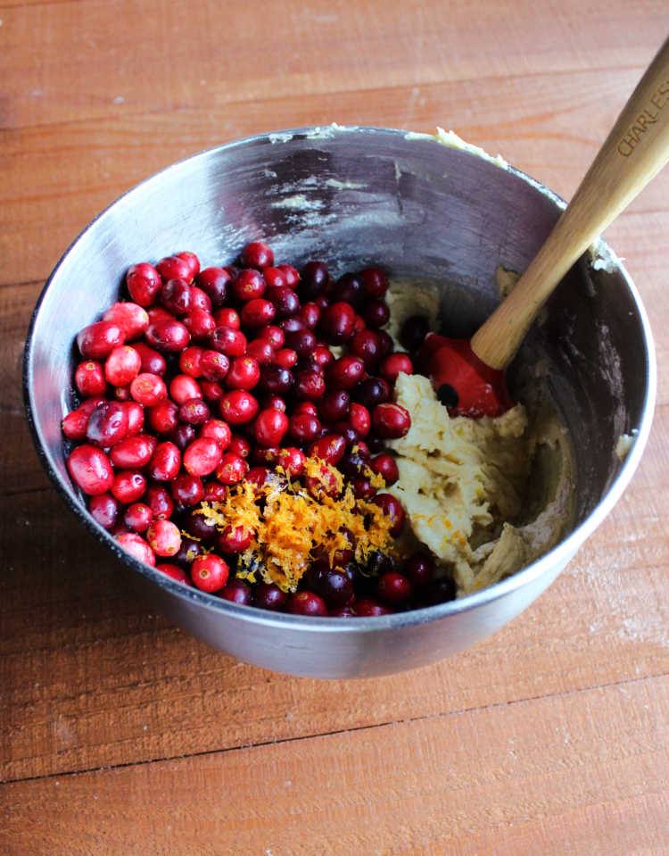 mixer bowl filled with batter, fresh cranberries and orange zest ready to be mixed.