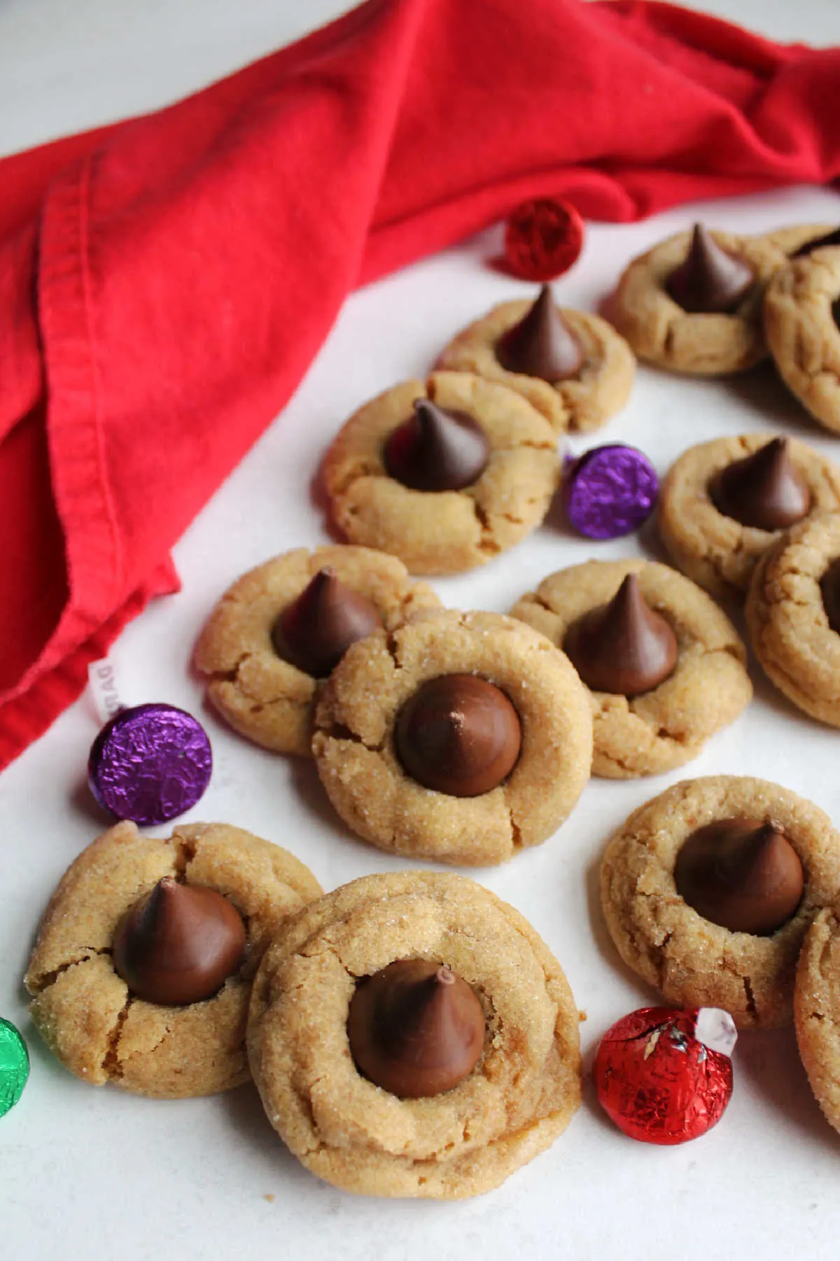 piles of peanut butter blossom cookies with candy kisses around them.
