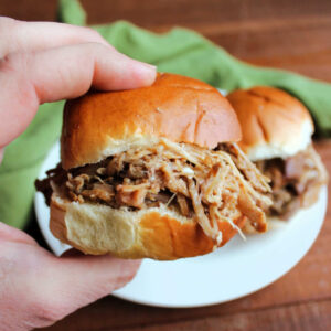 hand holding slider piled high with pineapple pulled pork