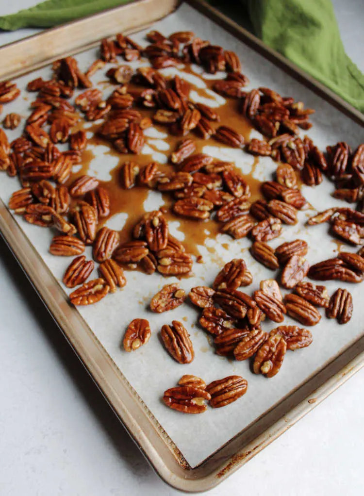 honey coated pecans cooling on parchment paper.