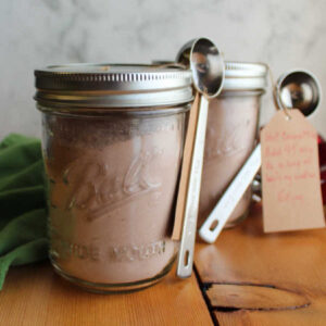 jars of hot chocolate mix tied up with measuring spoons and instructions for making hot cocoa, ready to be gifted.