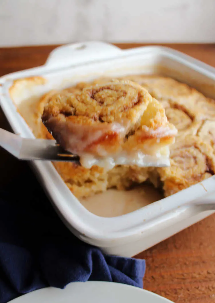 lifting gooey cinnamon butter roll out of pan.