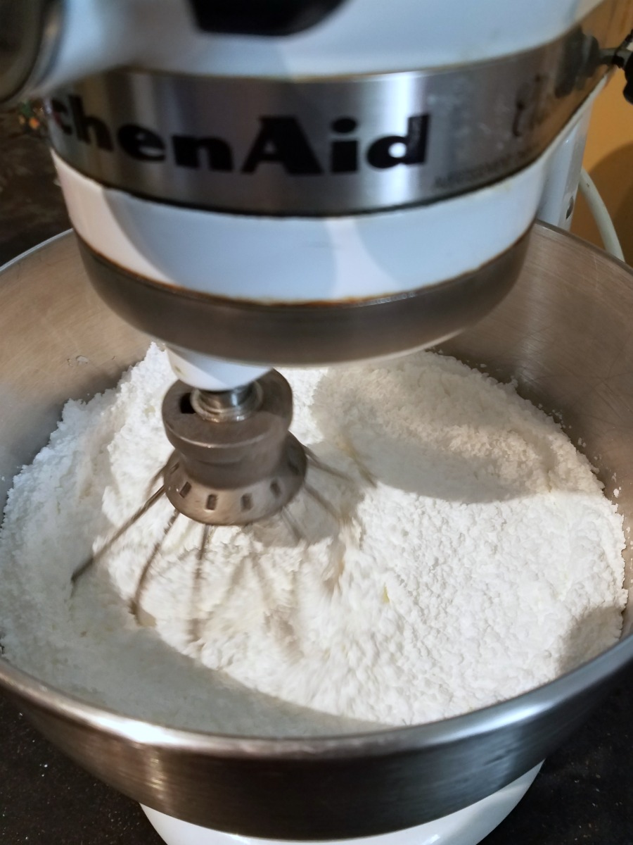 Mixer filled with powdered sugar and meringue powder being combined.