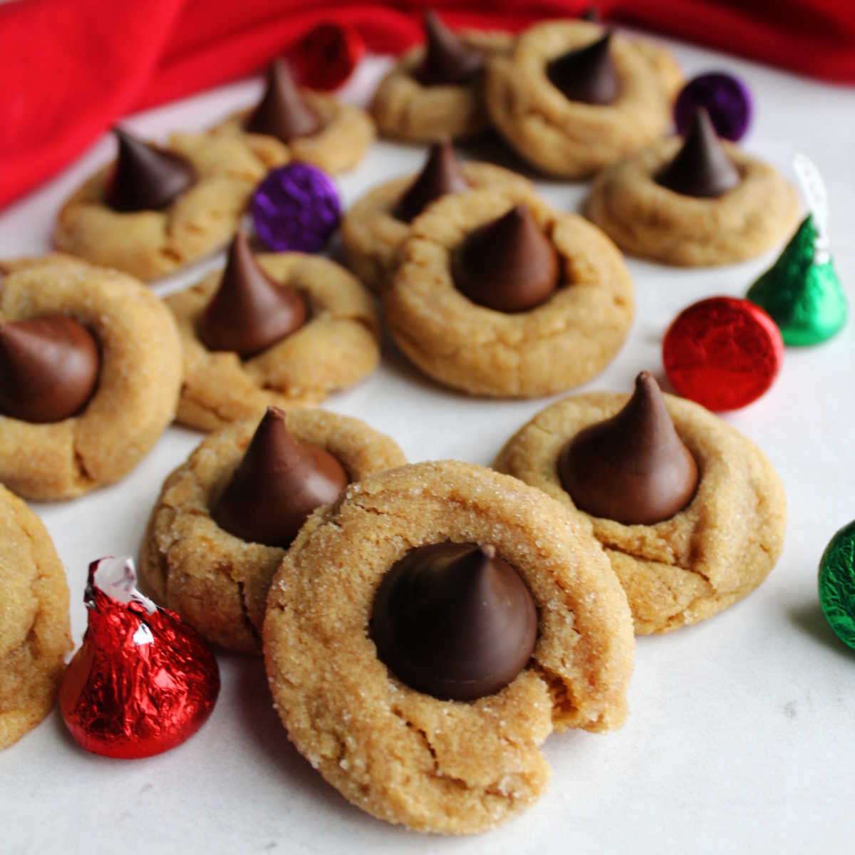 Soft peanut butter blossoms with different Kisses in the center including milk chocolate, dark chocolate, and caramel filled with some wrapped Hershey's Kisses nearby.