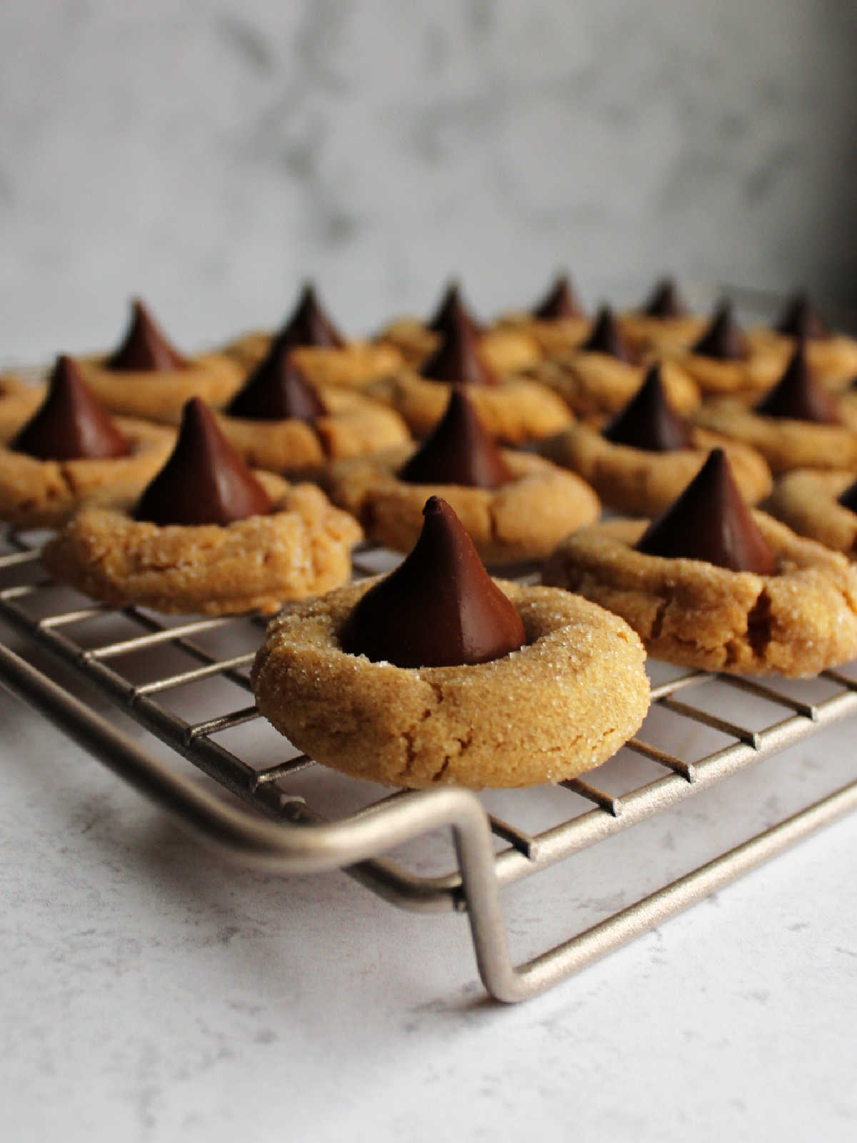 Chewy peanut butter blossom cookies with milk and dark chocolate kisses on cooling rack
