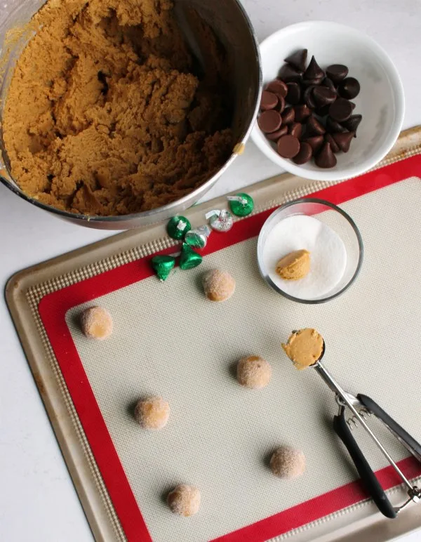 bowl of peanut butter cookie dough being rolled into balls to become blossom cookies.