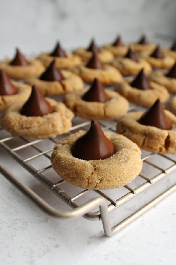 chewy peanut butter blossom cookies with milk and dark chocolate kisses on cooling rack
