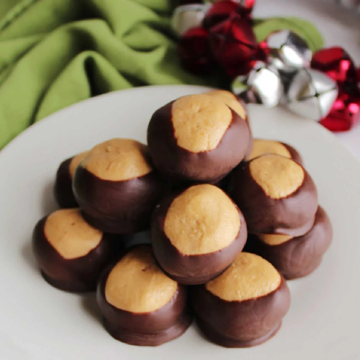 Pile of buckeyes on plate showing creamy peanut butter center showing through chocolate shell.
