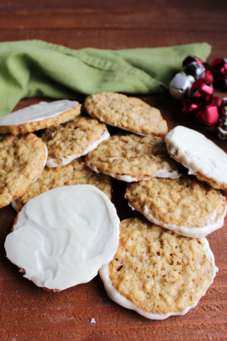 pile of white chocolate dipped frostbite cookies with jingle bells in the background.
