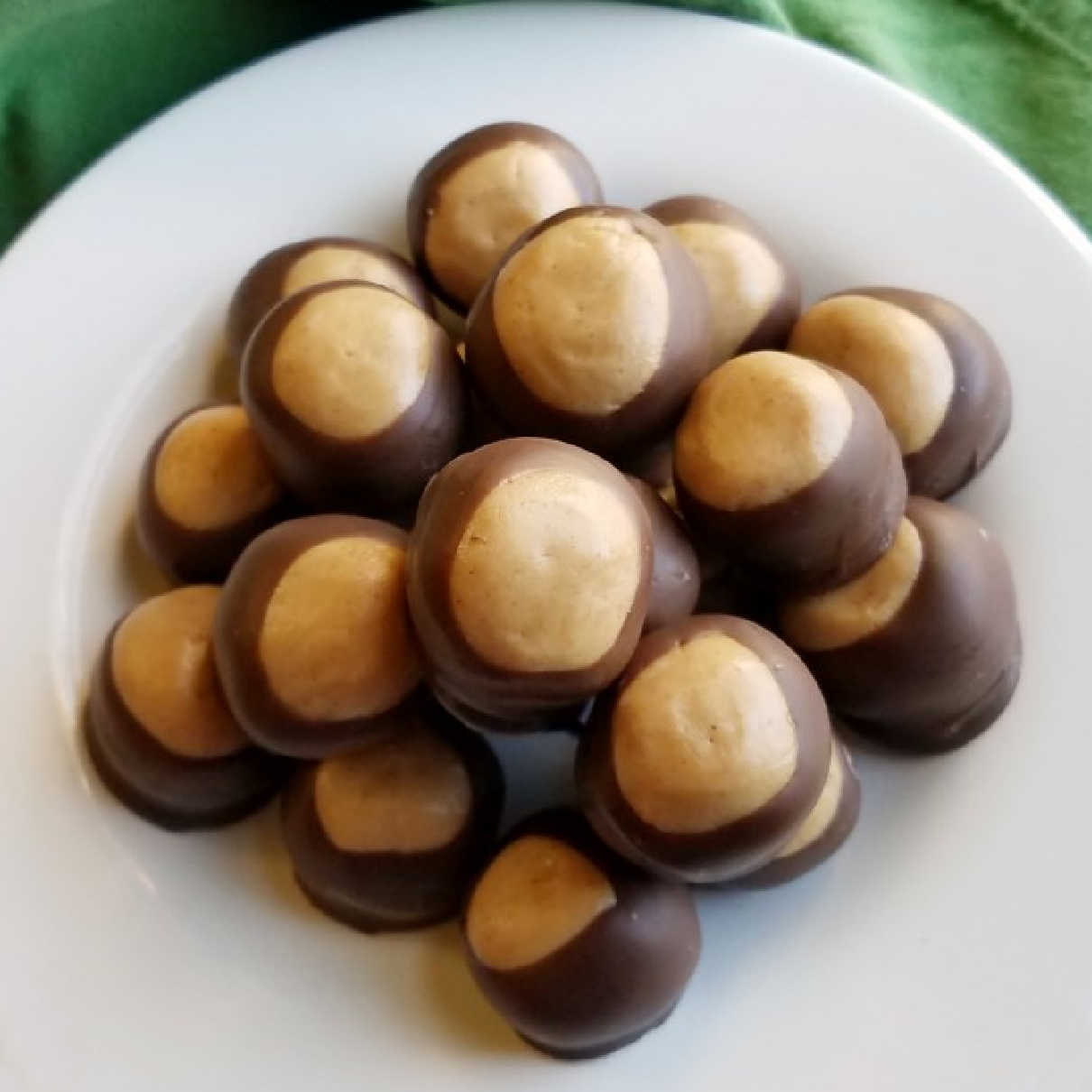 Pile of homemade buckeye candies with peanut butter center showing through chocolate shell.