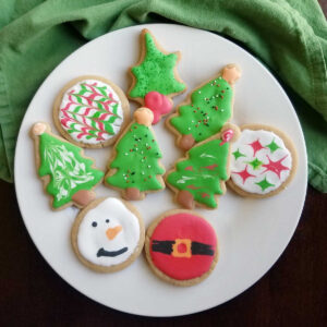 plate of peanut butter cookies cut into Christmas shapes and decorated with royal icing.