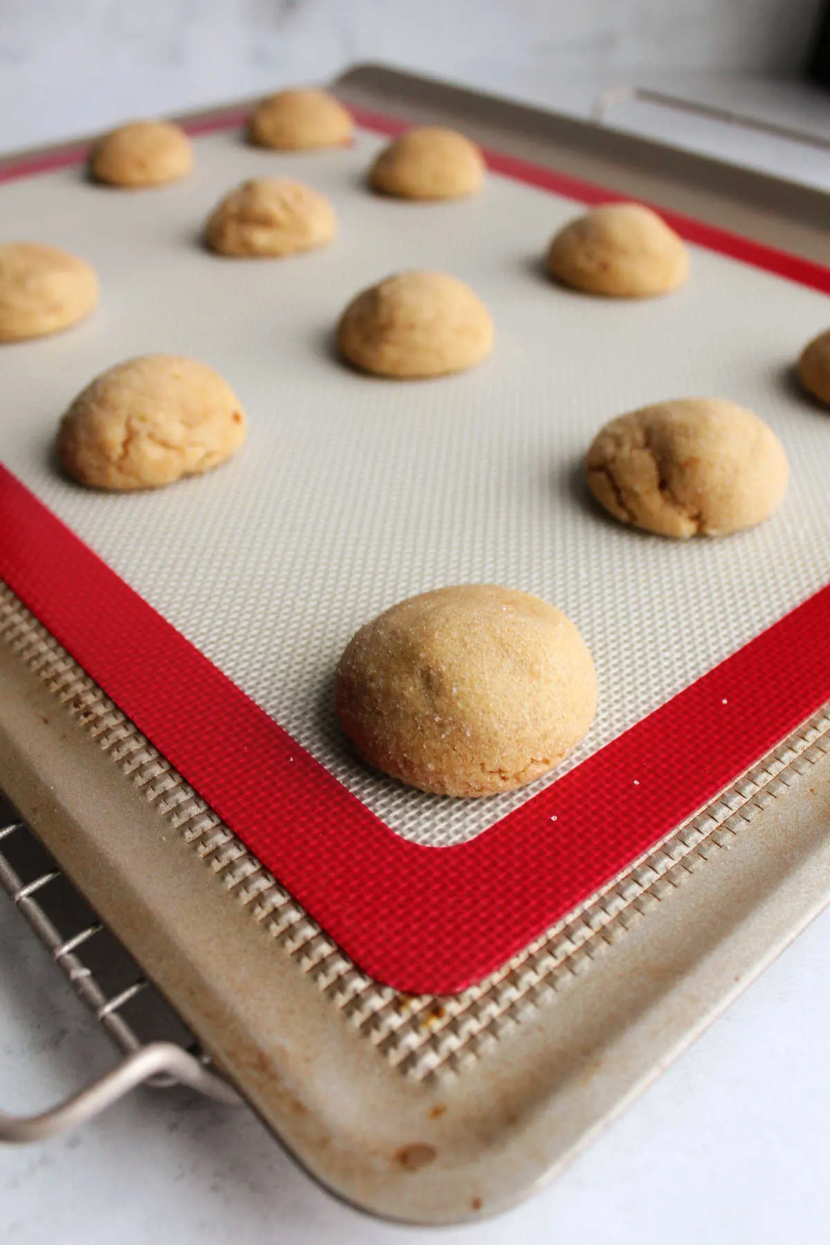 warm peanut butter cookies on baking tray, fresh from the oven and waiting for their chocolate kisses.