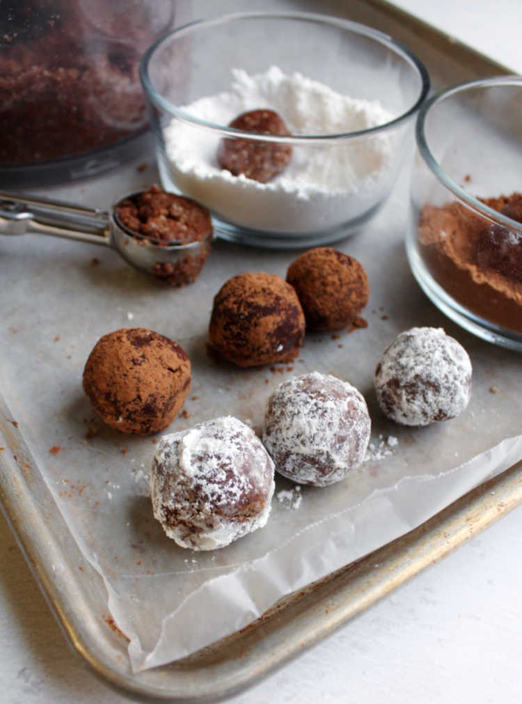 rolling rum balls in powdered sugar and cocoa powder.