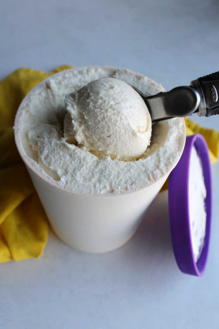 ice cream scooper dipping into container of lemon ice cream.