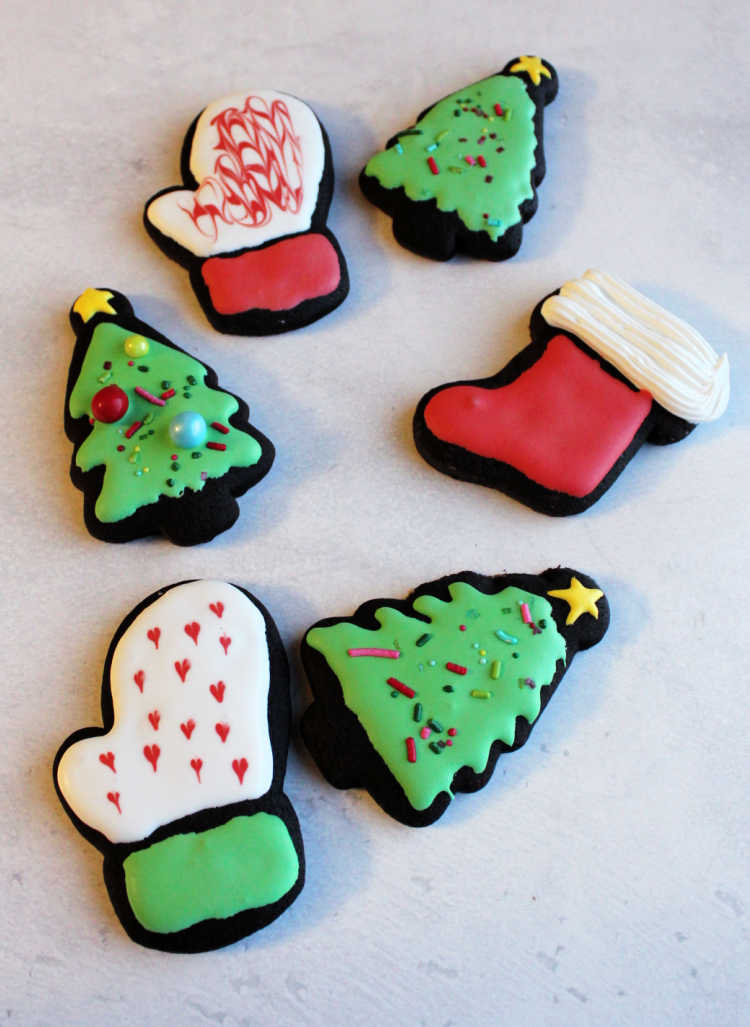 dark chocolate cookies cut into Christmas shapes and decorated with royal icing.