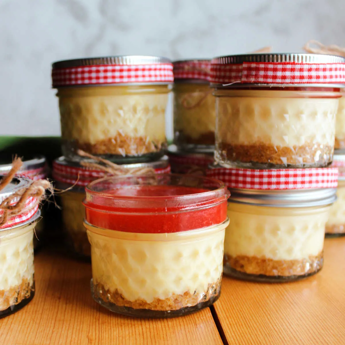 jars of cheesecake with graham cracker crust and strawberry topping.