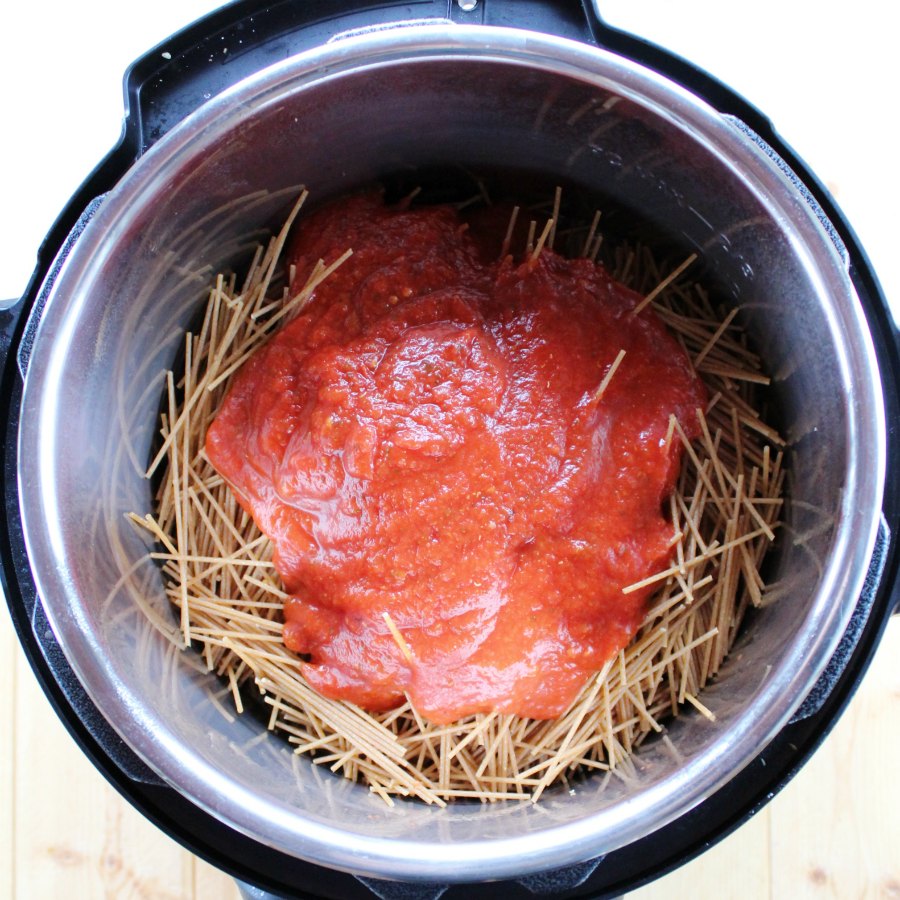 Dry spaghetti in instant pot with tomato sauce on top.