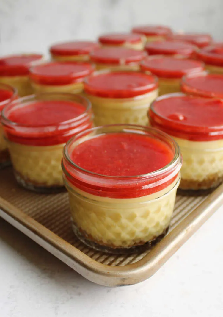 little jars of strawberry topped sweetened condensed milk cheesecake ready to chill