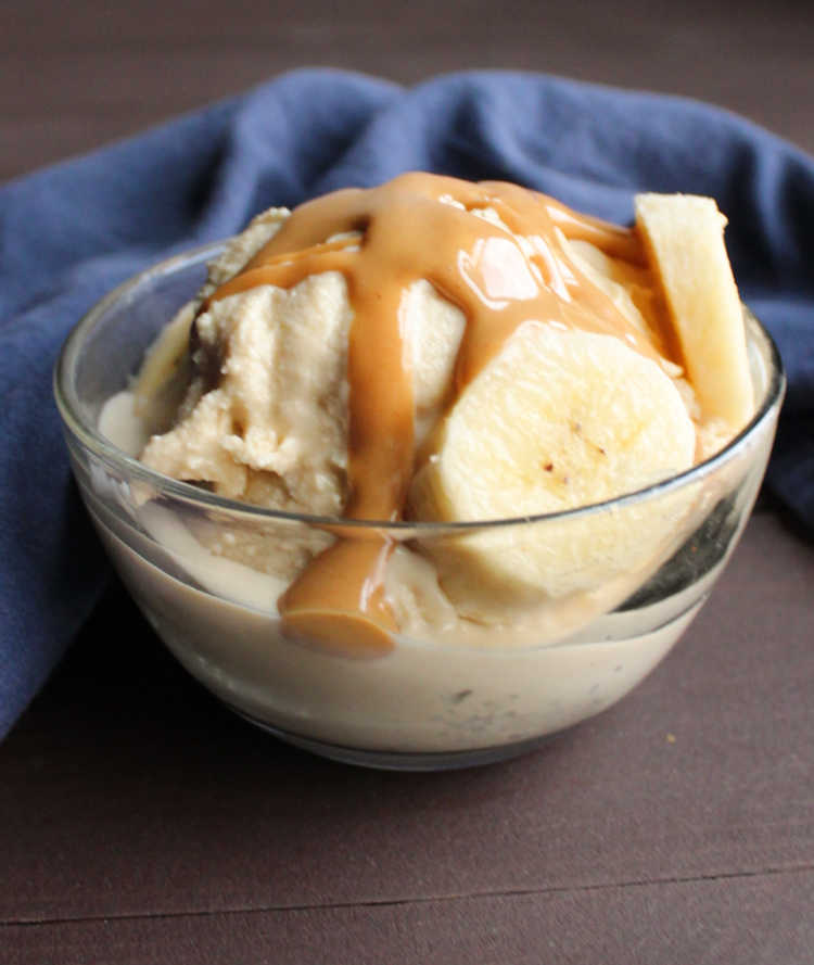 glass bowl with ice cream, peanut butter magic shell and banana slices.