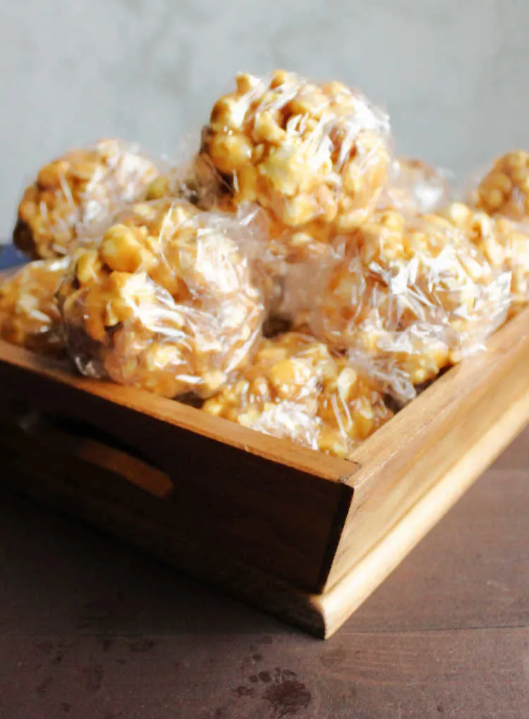 wooden basket filled with peanut butter popcorn balls wrapped in plastic.