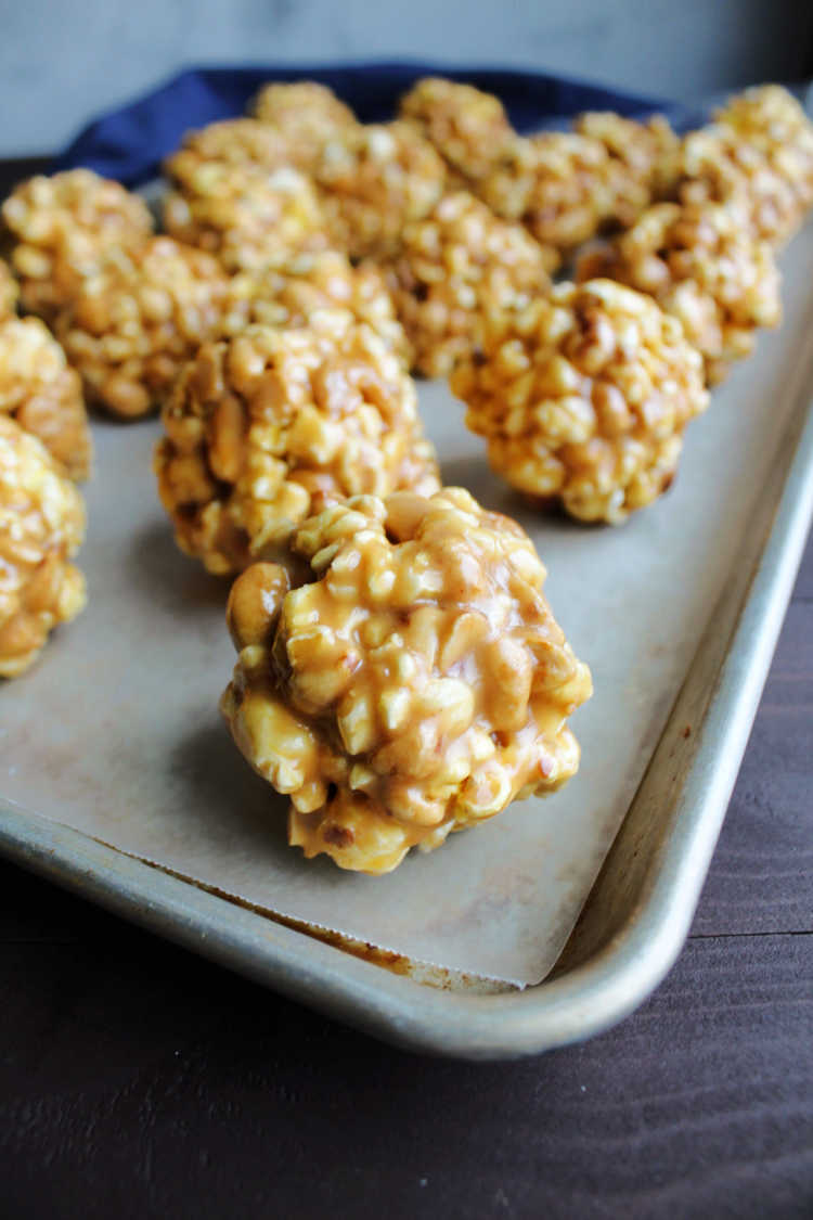 peanut butter popcorn balls cooling on wax paper lined cookie sheet.