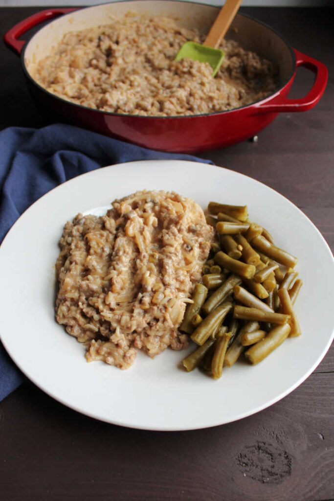serving of creamy ground pork and rice in front of skillet of remaining dinner.