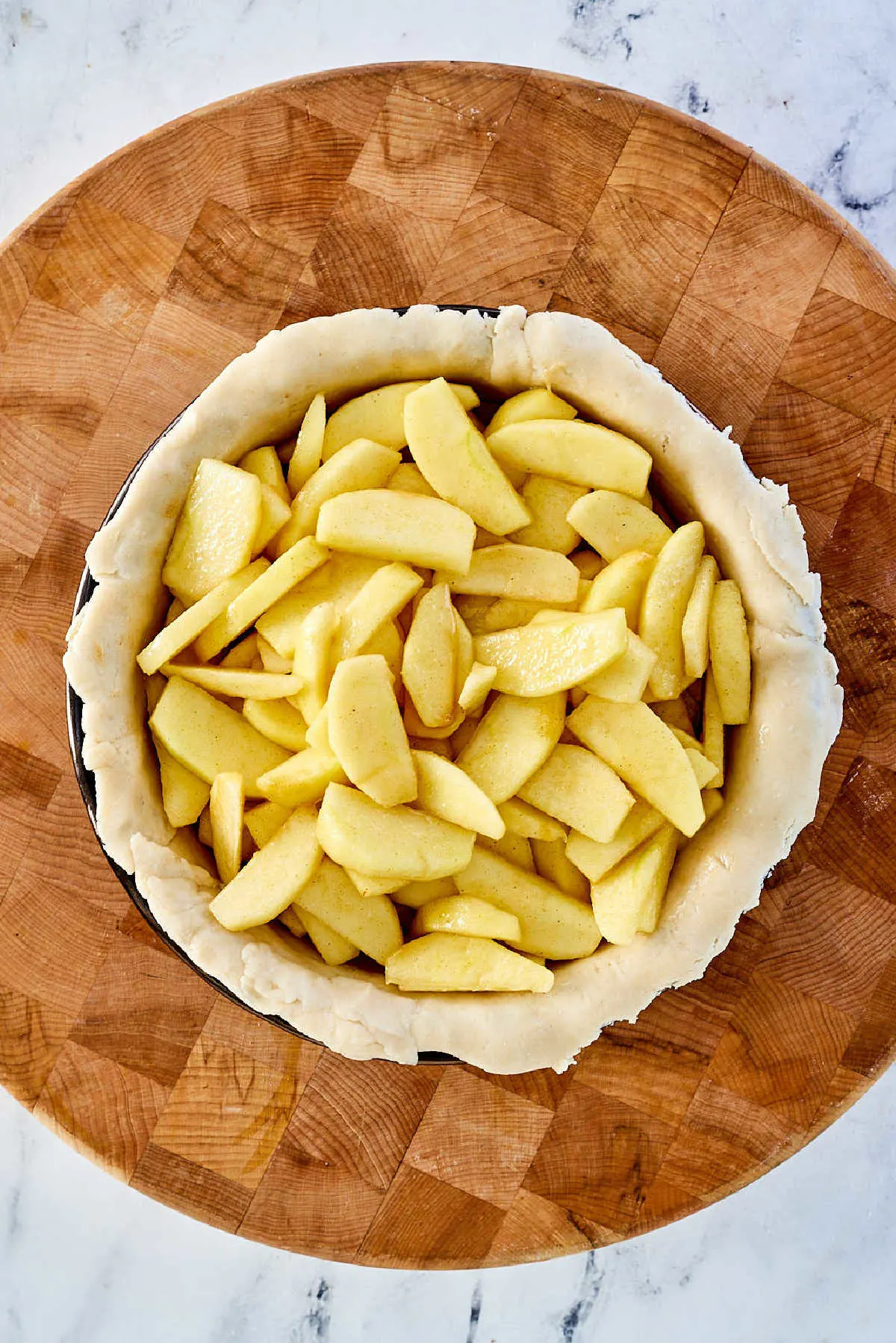 Apple slices in pie crust in pan.