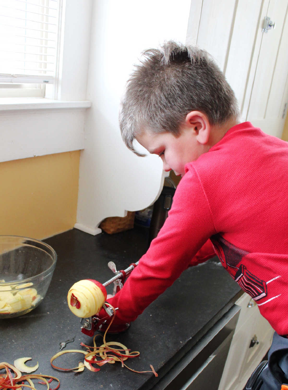 Little dude using the apple peeler, corer, slicer to get apples ready for pie.
