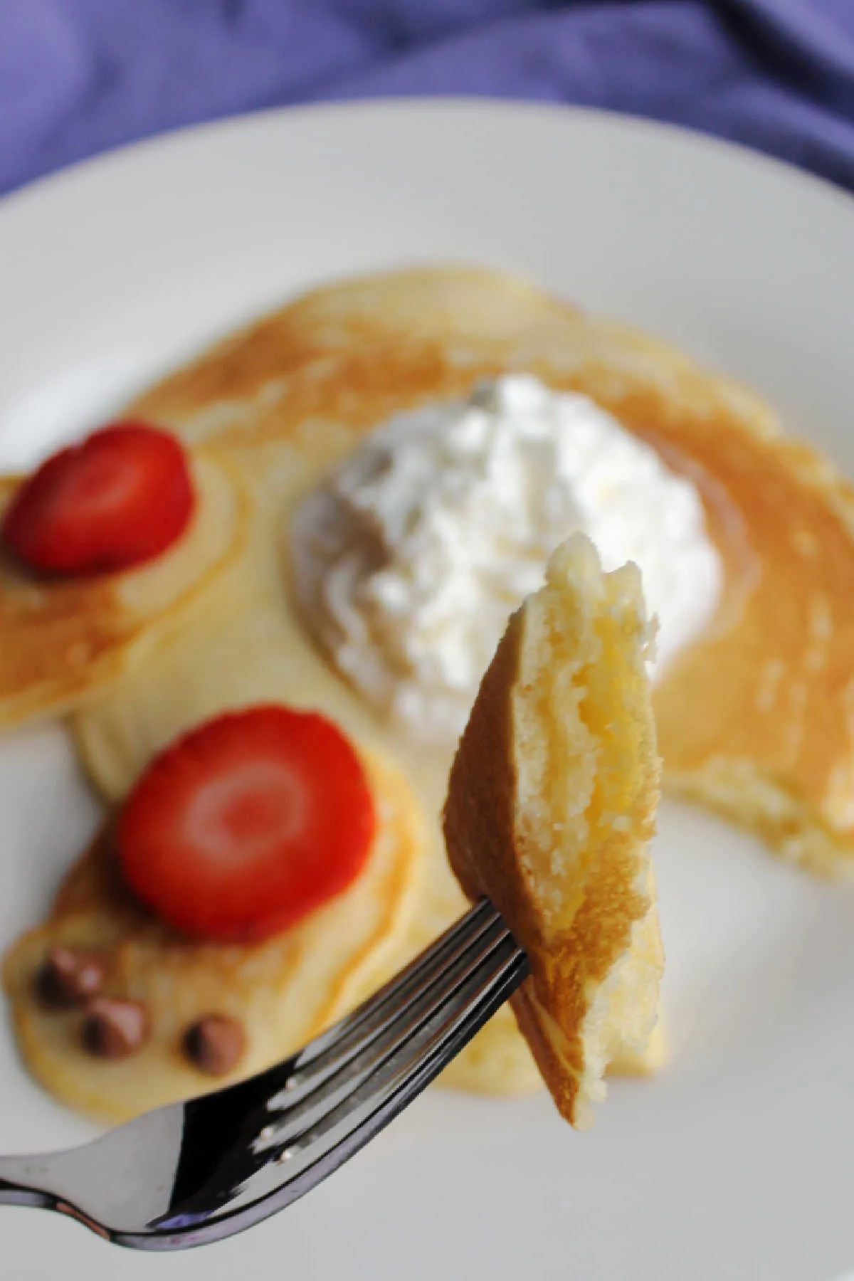 bite of fluffy pancake on fork, bunny butt pancake in background.