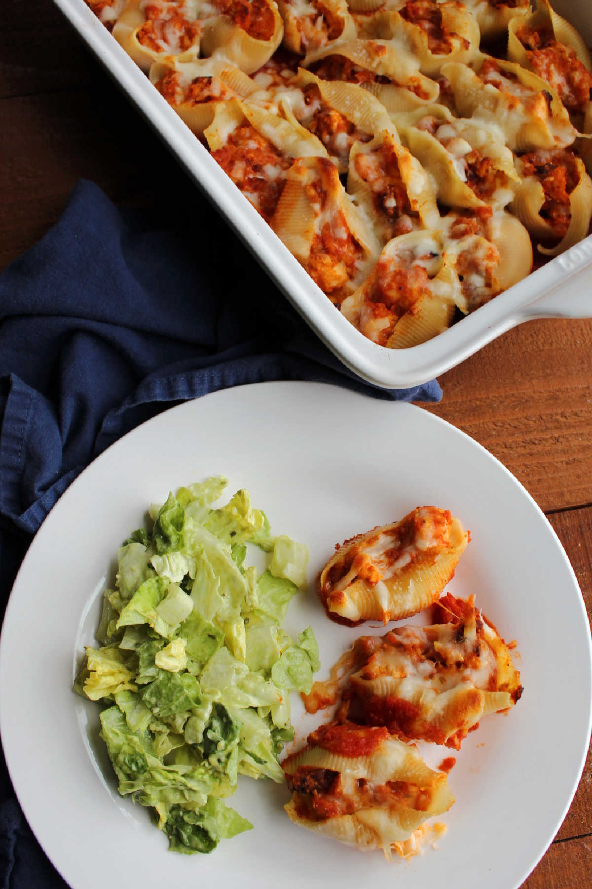 Chicken parmesan stuffed shells served on plate with a green salad.