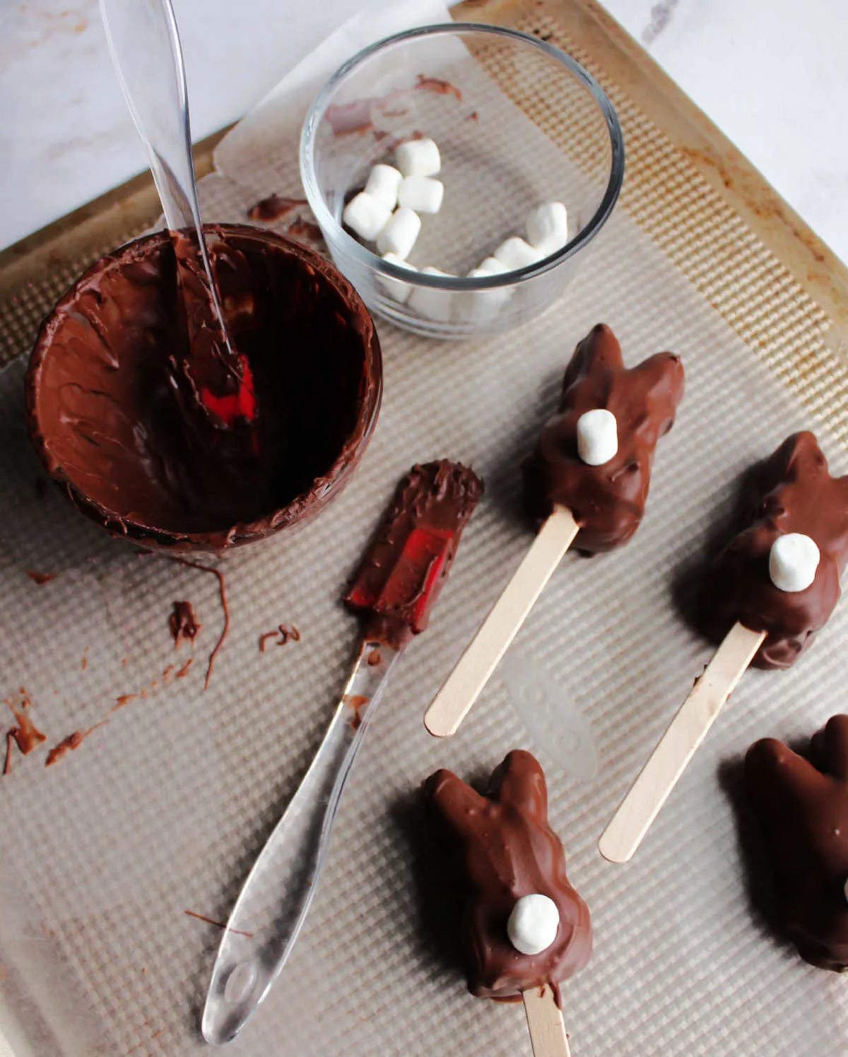Chocolate coated marshmallow bunnies setting up on wax paper.