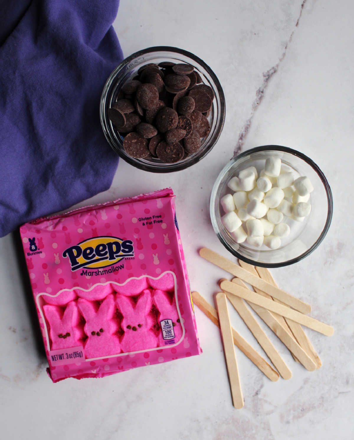 package of bunny Peeps, popsicle sticks, bowl of chocolate and mini marshmallows ready to be assembled. 