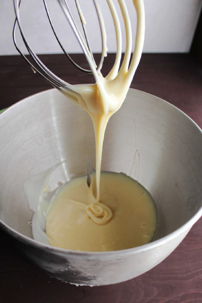 really thick and cold sweetened condensed milk dripping off of mixer beater, ready to be whipped.