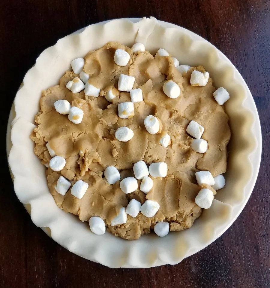 pie crust filled with peanut butter cookie dough and mini marshmallows, ready to bake. 