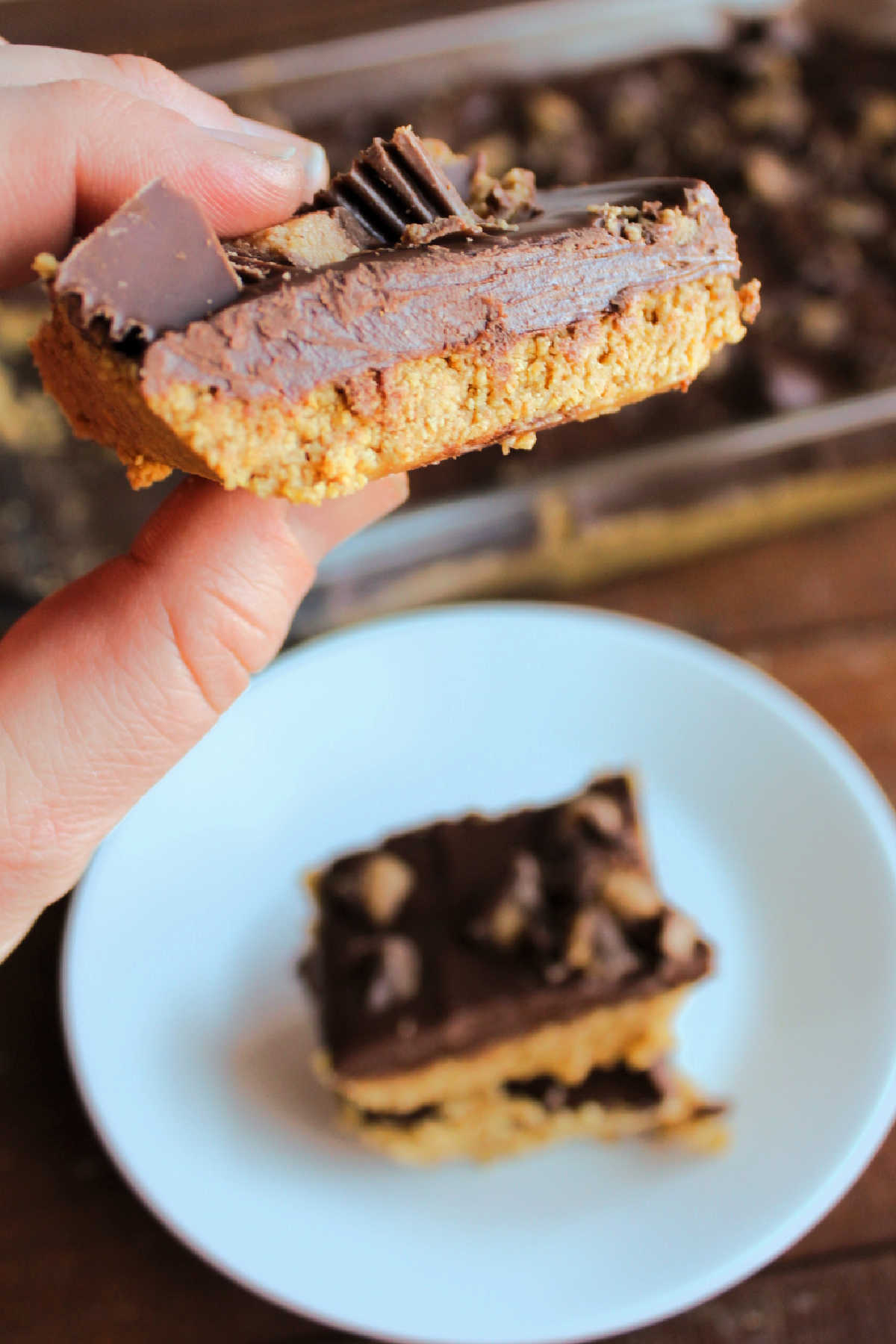 Hand holding peanut butter bar with chocolate topping, ready to eat. 