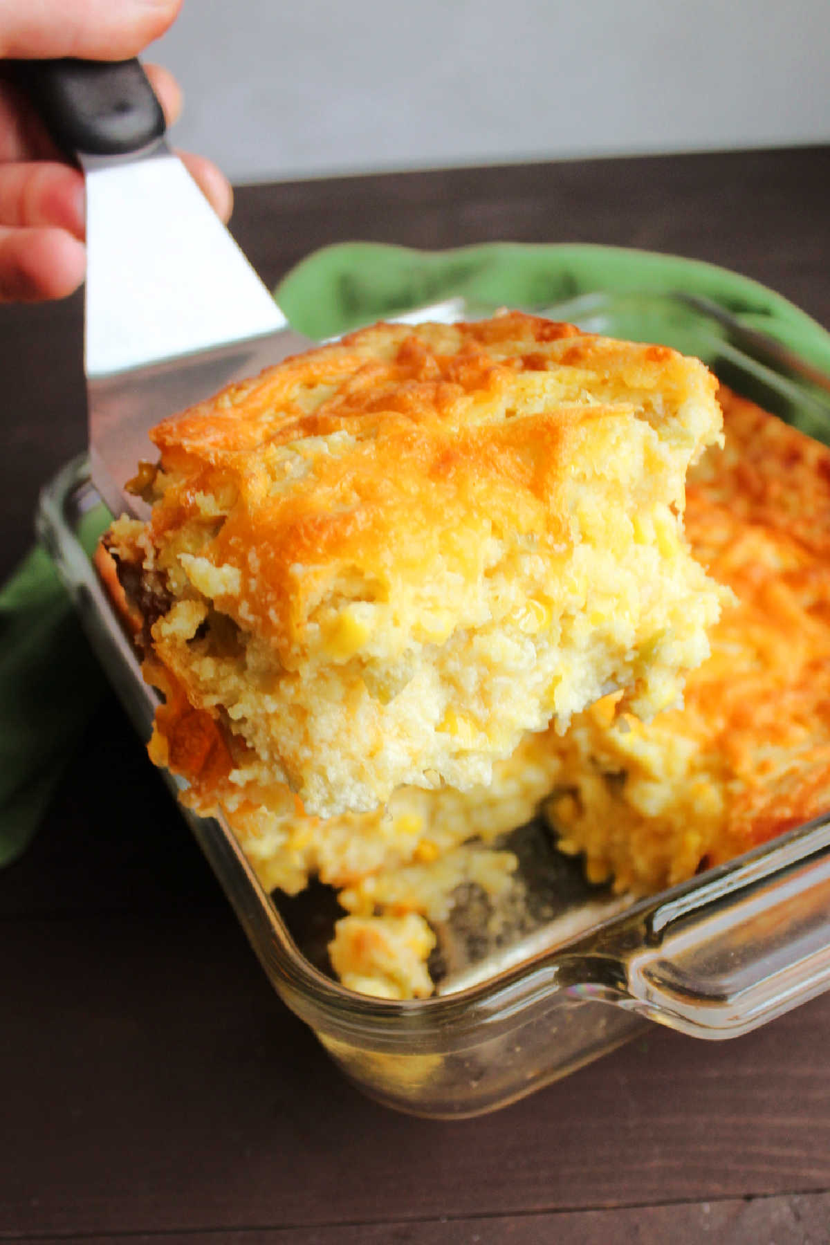 spatula lifting out slice of chili cheese corn casserole showing soft interior.