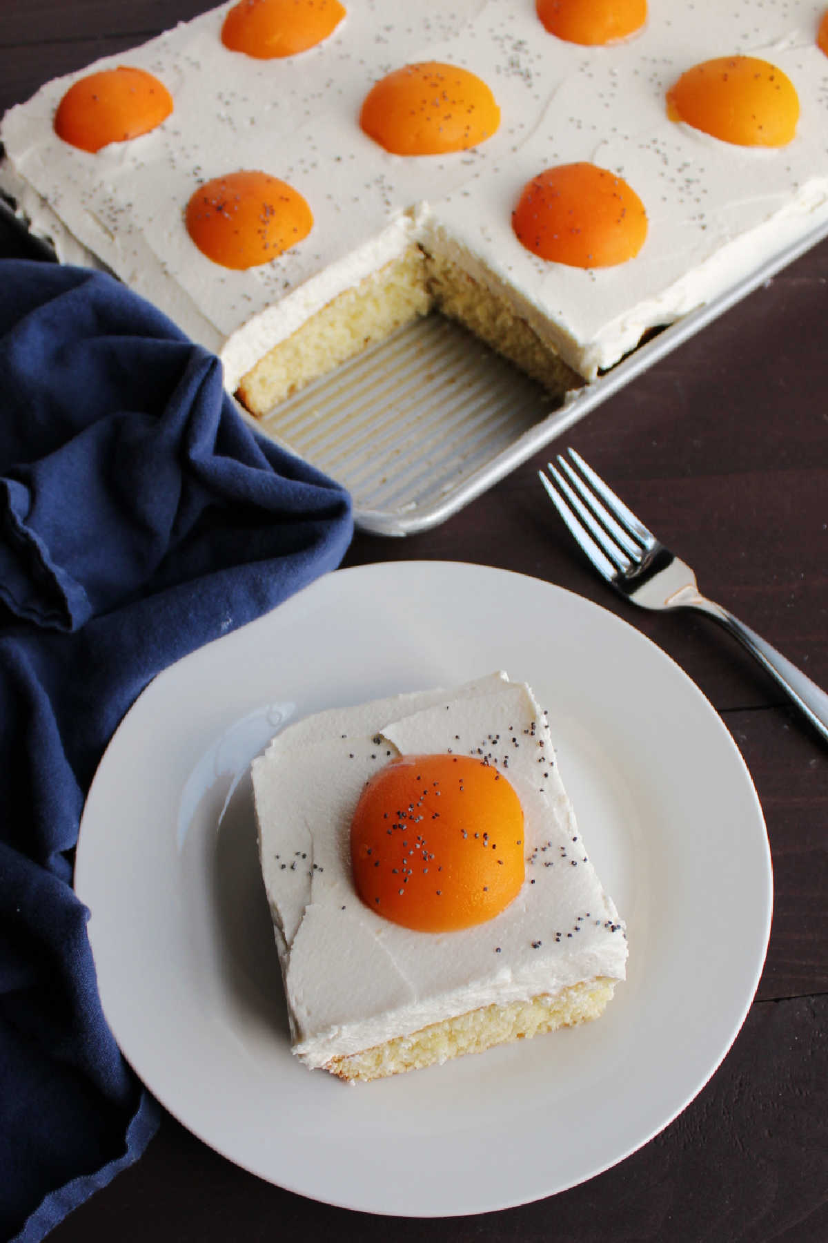slice of cake that looks like a sunny side egg in front of remaining sheet cake decorated with several apricot egg yolks.