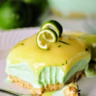bite of layered lime sherbet bar on fork showing cracker crust, creamy sherbet center and bright lime curd topping.
