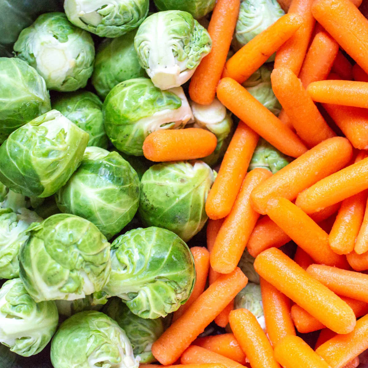 fresh Brussels sprouts and carrots next to each other.