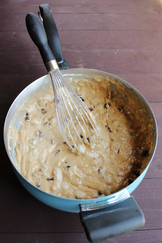 saucepan with raisin cake batter and whisk inside, ready to be poured into pan.