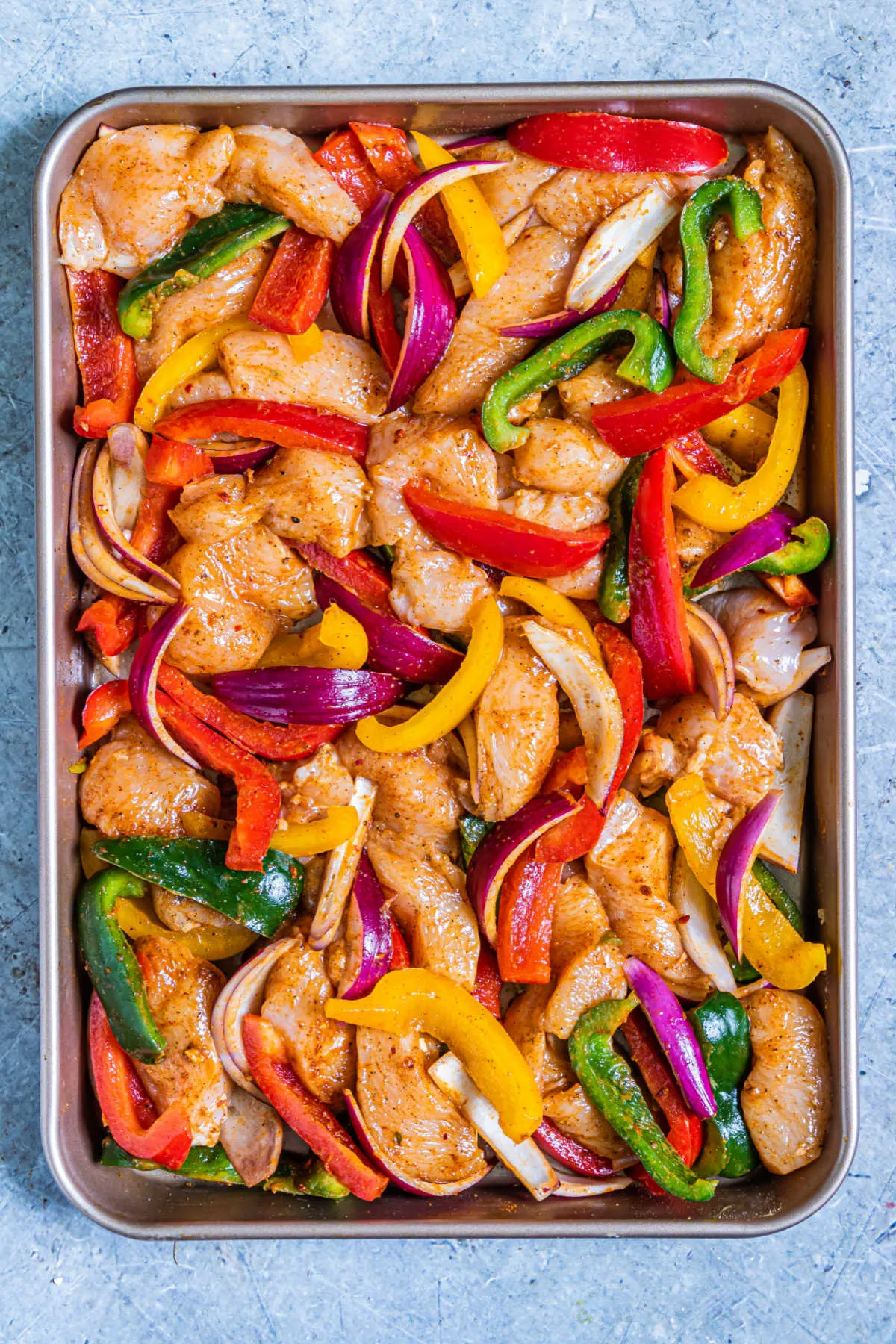 chicken fajita ingredients tossed with oil and seasoning, ready to bake.