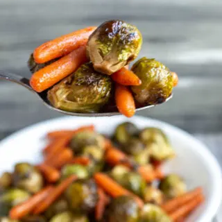 Spoonful of honey roasted brussels sprouts and carrots, ready to eat.