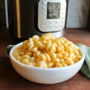 Bowl of creamy curly mac and cheese in front of instant pot.