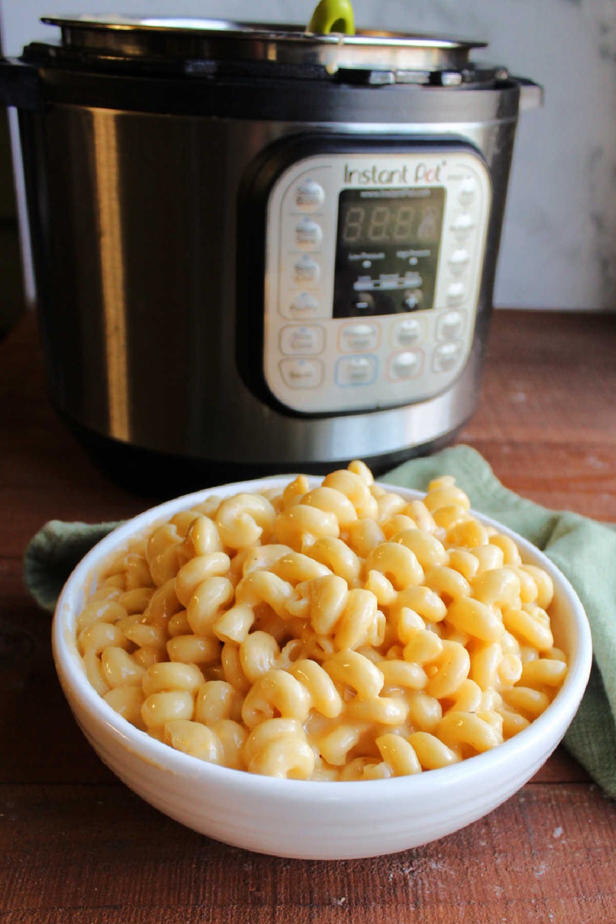 Bowl of curly mac and cheese in front of Instant Pot.