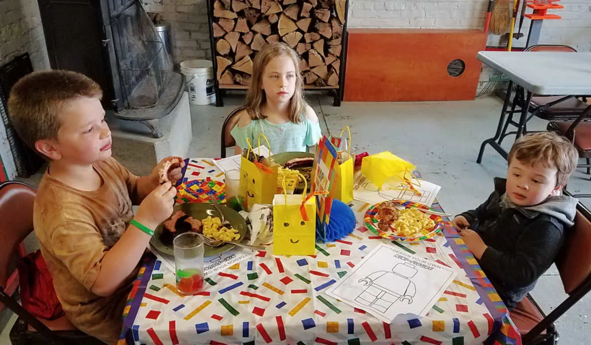 Kids table with Lego coloring sheets, treat bats and kids eating dinner.