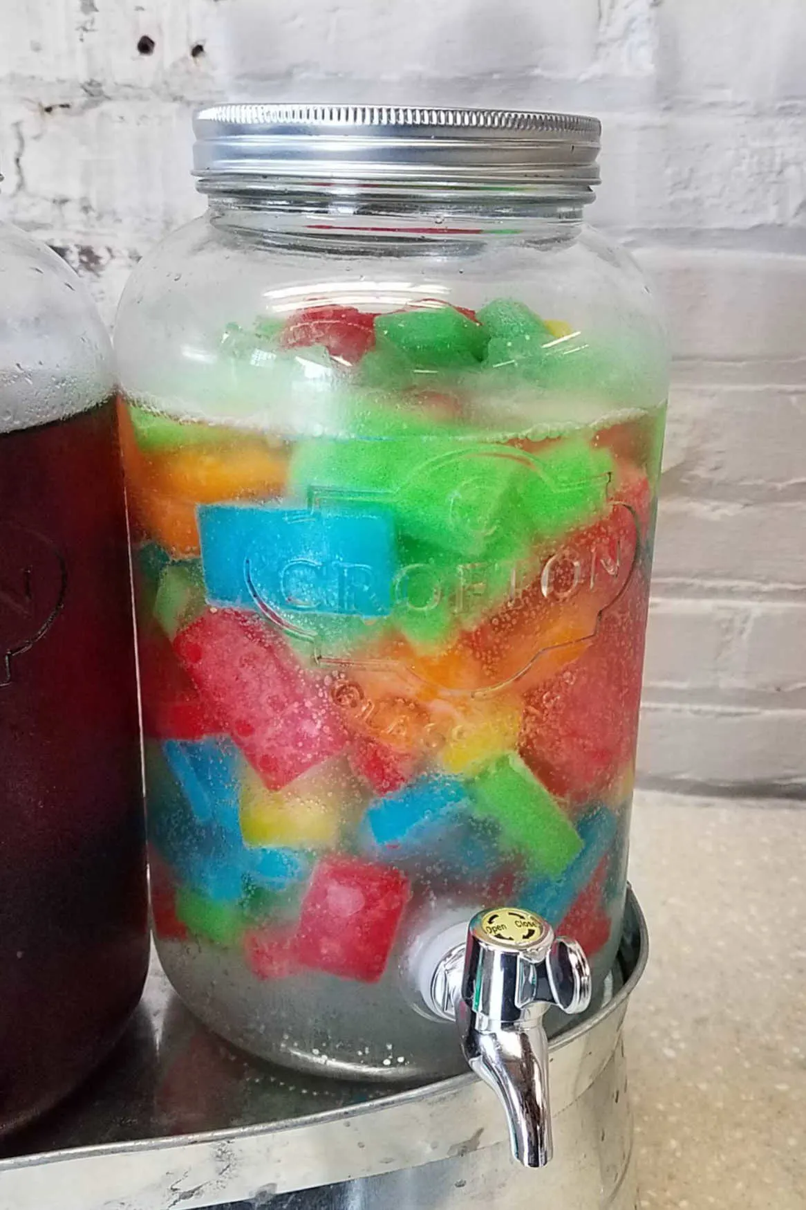 Colorful lego shaped ice made from jello floating in sprite in drink dispenser.